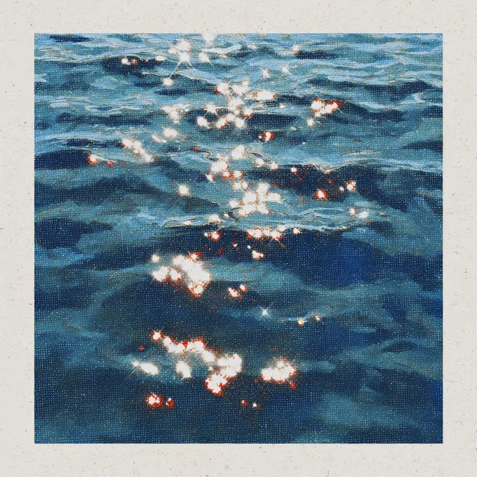 An artistic photograph of dark blue water with sparkling sunlight reflections, presented as a Polaroid-style print with a white border.