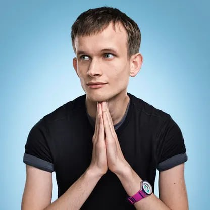 A young man in a black t-shirt stands against a light blue background with his hands pressed together in a prayer-like gesture, gazing thoughtfully to the side. The image likely represents Vitalik Buterin, the Ethereum co-founder mentioned in the post about Nethermind's Beacon Chain plugin being synced for the Sepolia Glamsterdam hard fork on October 6.