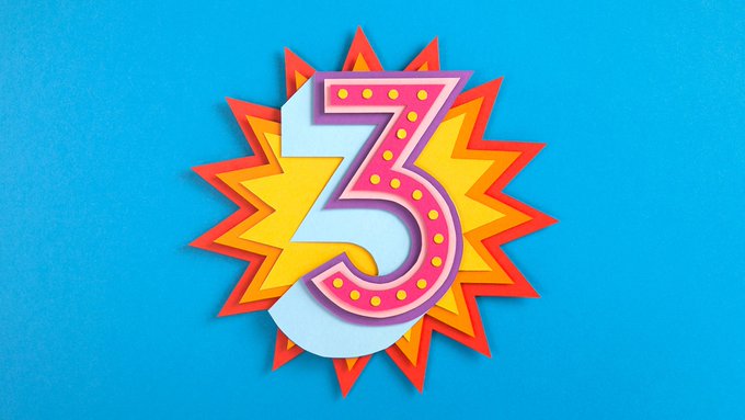 In the image, there is a 3-decade-old number, specifically "3", which appears as a vibrant and eye-catching piece of paper art against a blue background. The design features an explosion or fire-like shape with the number three prominently displayed in red, yellow, pink, and orange colors. This artistic representation may indicate that it is a celebration or commemorative event related to this particular number.