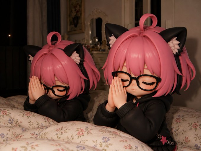 Two pink-haired anime figurines with cat ears and black glasses sit with their hands clasped in prayer on a floral-patterned surface, eyes closed in a serene expression.