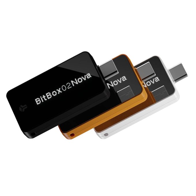 Three BitBox02 Nova hardware wallets are displayed in black, orange, and white against a white background.