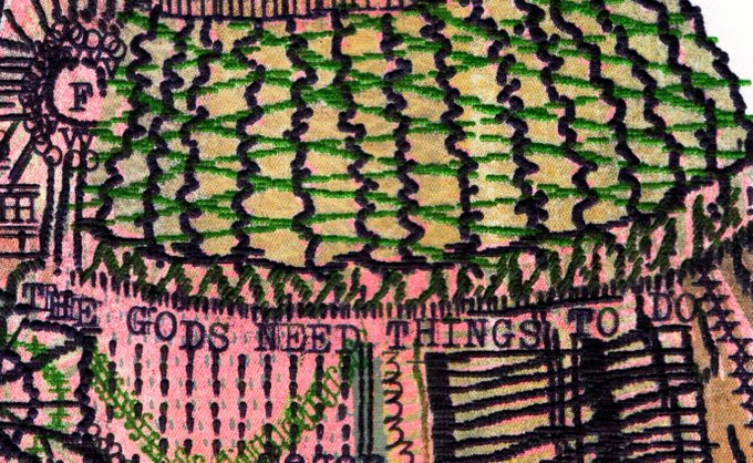 A detailed close-up of intricate embroidery or textile artwork featuring colorful pink, green, and yellow stitching with the text 'THE GODS NEED THINGS TO DO' visible across the design.