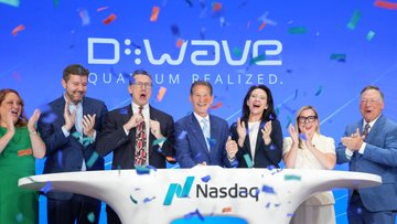D-Wave Quantum ($QBTS) executives celebrate their listing on the Nasdaq, ringing the ceremonial bell on a stage featuring the company's "Quantum Realized" branding. Confetti rains down as the team marks the milestone of joining the Nasdaq market.