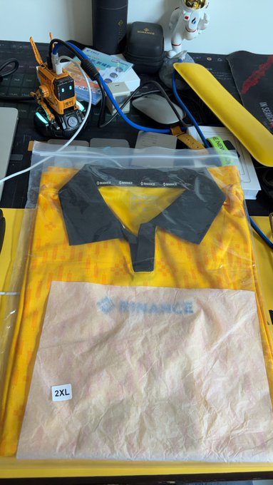 The image shows a yellow polo shirt placed inside a clear plastic bag, which appears to be new or unused. The bag has a label that reads "2xl" and "New", indicating its size and condition. The background of the image is white with some text visible in the corner. The post seems to be promoting a product or service related to clothing items like polo shirts.