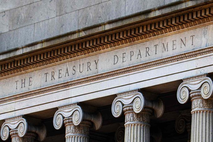 This image shows the entrance of the Treasury Department building, featuring classical columns and an engraved stone facade with the words 'THE TREASURY DEPARTMENT'.