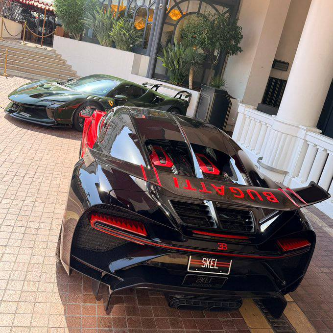 Two Bugattis—one black and red with "BUGATTI" lettering on the rear wing and a license plate reading "SKEL"—are parked outside an upscale venue, matching the Instagram giveaway by @skel offering $300 to two wallet-commenting followers. The post showcases the luxury cars as a flex to promote the cash giveaway.