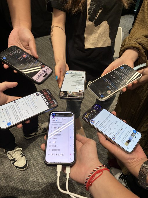 A group of attendees at the OKX Hangzhou Meetup Base gather together, holding their smartphones in a circle with various social media posts and messages visible on their screens. The image captures the collaborative spirit of the crypto community event, with participants sharing their online presence following the wrap-up meeting.