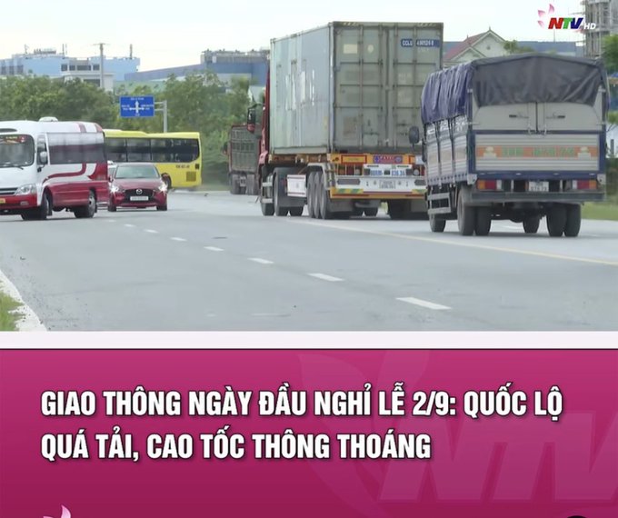 Vietnamese news broadcast showing traffic on a highway with trucks and buses, with headline 'GIAO THÔNG NGÀY ĐẦU NGHỈ LỄ 2/9: QUỐC LỘ QUÁ TẢI, CAO TỐC THÔNG THOÁNG' (Traffic on first holiday day).