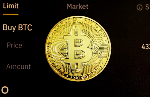The image features a close-up view of an old Bitcoin coin, highlighting its unique design and history within the cryptocurrency world. The prominent gold color of the coin draws attention to its monetary value and historical significance. The background appears to be a screen with some text, possibly providing context or information about the coin's market price and how it is perceived by those who are interested in investing or understanding Bitcoin's evolution.