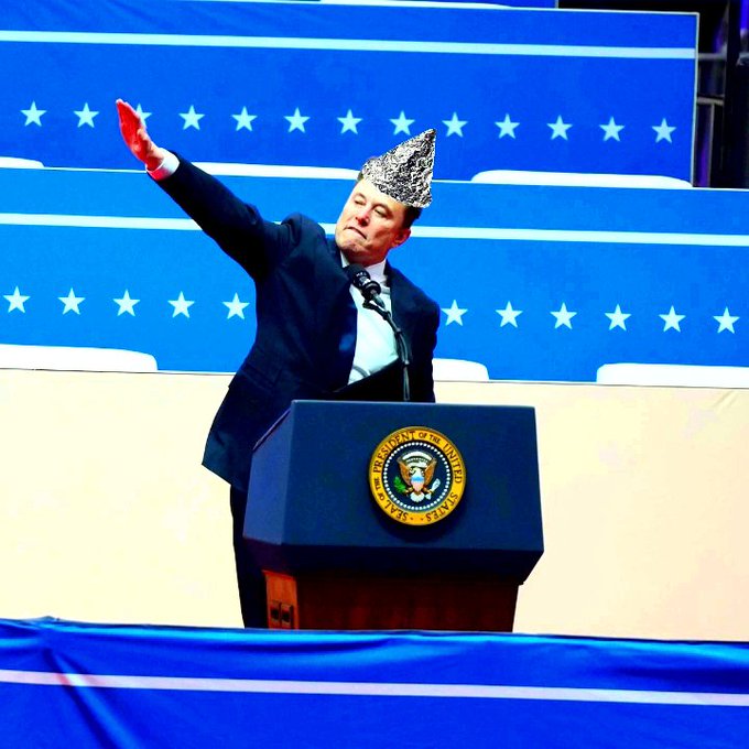 A man in a suit stands at the presidential podium bearing the United States seal, performing a Nazi salute with a tin-foil hat on, with an American flag-themed background behind him.