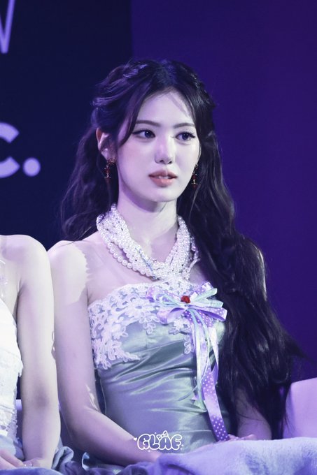 A young woman with long dark hair wearing an elegant light blue dress with a pearl-embellished neckline and a decorative bow, appearing to be at an event.