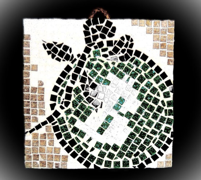 The image features a mosaic art piece that depicts a green and white hexagonal shape with a black border, resembling a coin or token. The artwork has been created using small square tiles arranged in a grid-like pattern, giving it a unique and intricate appearance. The colors used are predominantly green and white, which adds to the overall aesthetic appeal of the piece. The image also includes text that reads "Cryptomosaic 21/21 cm - Bitcoin Green - Fire / Logo / Green Bitcoin - The -Eco - Friendly alternative - is a new cryptocurrency that allows holders to #stake their tokens #utilizing the revolutionary Gamefield Staking mechanic".