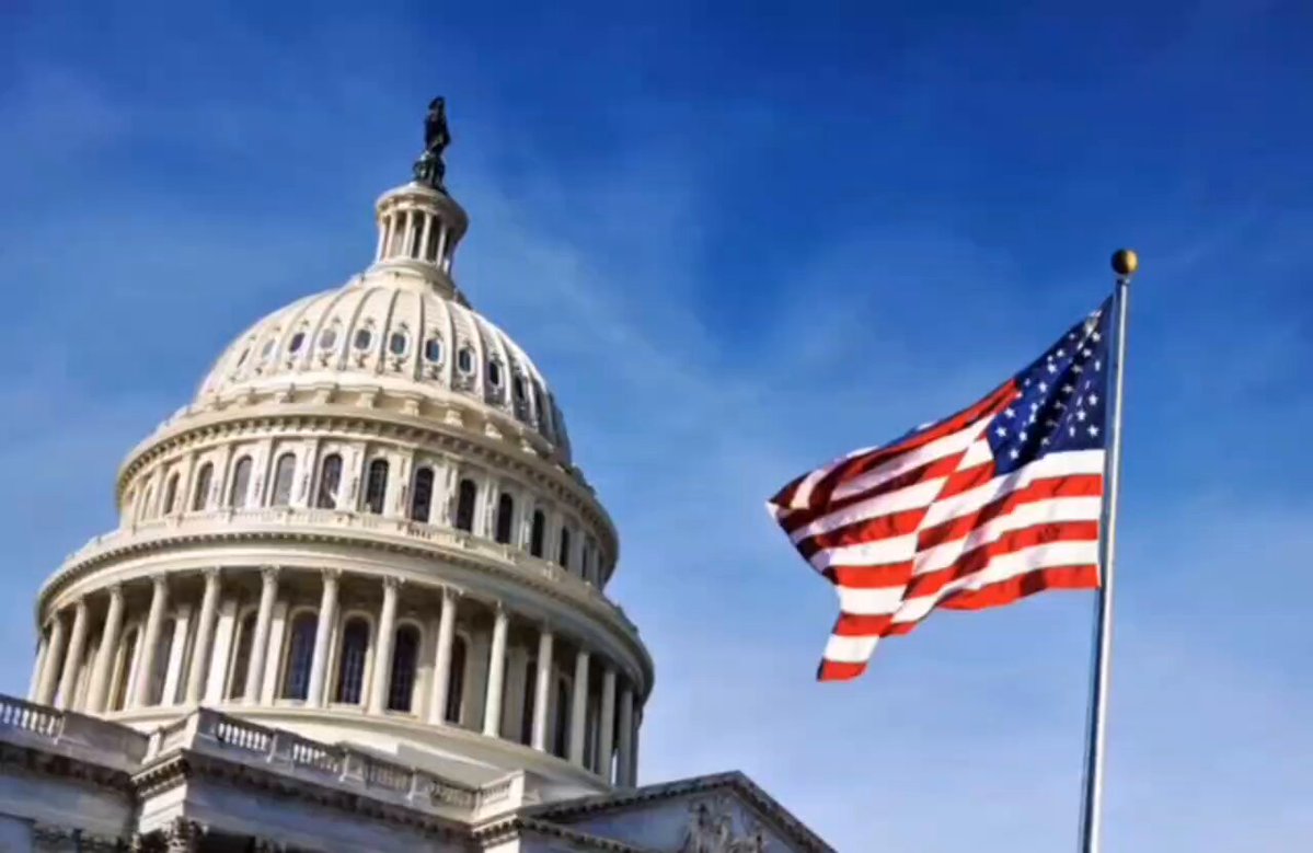 The image features a large white building with an American flag flying above it against a blue sky. The scene appears to be set at the U.S. Capitol Building, which has been described as "the most beautiful building in the world". The image also includes text that reads "XRP & CRYPTO TAXES House Republicans have introduced seven tax bills focused on XRP and cryptocurrencies ahead of next week's hearing." This suggests that there might be discussions or debates about cryptocurrency regulations and taxation.