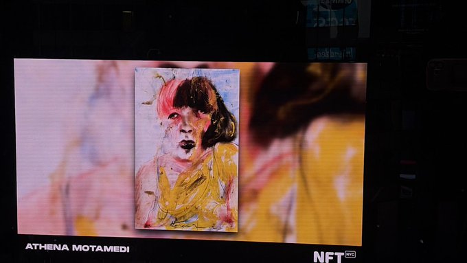 An NFT NYC event display showing an abstract expressionist painting of a figure in yellow and pink with dark hair, credited to ATHENA MOTAMEDI, projected on a large screen with an NFT NYC logo.