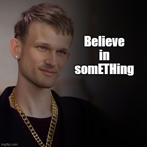 The image features a man wearing a gold chain necklace, with his face partially visible behind him. He has short hair and is smiling at the camera. The caption of the image reads "Believe in something. Even if it seems impossible, you have to." This message appears to be related to the main subject of the photo, which is the man wearing a gold chain necklace.