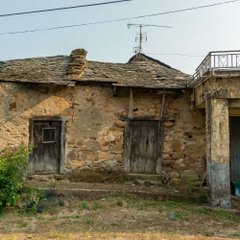 A crumbling, weathered stone building with a partially collapsed roof and aged wooden doors stands in disrepair, evoking neglect and decay. The image's depiction of a dilapidated structure visually represents the post's "Bitcoin $80K in 2025 vs $80K in 2026" message, symbolizing stagnation or deterioration despite the unchanged price.
