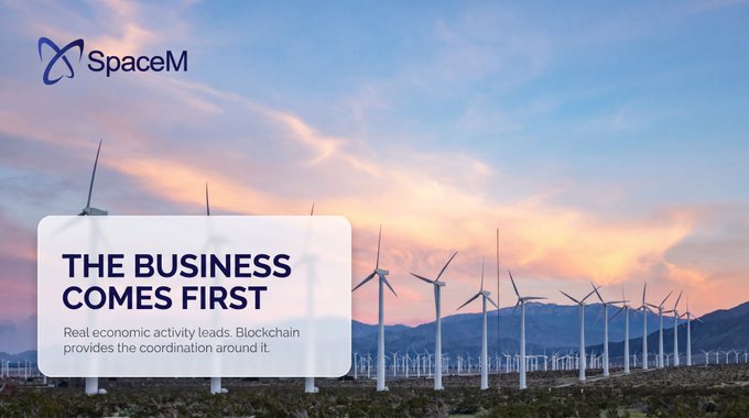 A promotional banner for SpaceM featuring wind turbines in a desert landscape, with text reading 'THE BUSINESS COMES FIRST' and 'Real economic activity leads. Blockchain provides the coordination around it.'