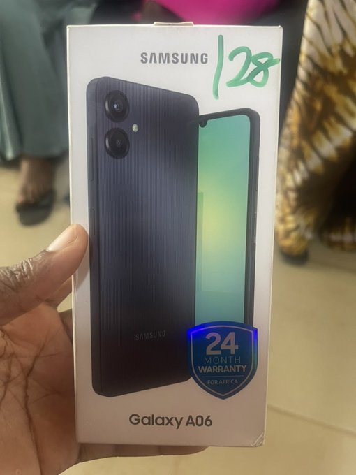 A hand holds a Samsung Galaxy A06 phone box with handwritten text '128' on it and a blue '24 MONTH WARRANTY FOR AFRICA' badge.