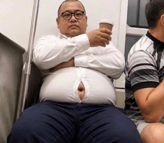 An older man wearing glasses and a white dress shirt sits on public transit holding a coffee cup, his shirt pulled up to expose a gap over his large belly button, while a person in a striped shirt sits next to him.