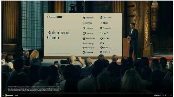 A man in a suit stands on stage presenting a slide titled "Robinhood Chain," which lists partner projects including Morpho, Layer Zero, Lighter, TRM, Uniswap, Fireblocks, Paxos, 1inch, Arbitrum, LLFI, alchemy, 0x, Chainalysis, RIALTO, Chainlink, and arcus, while an audience watches and takes photos. The image relates to the post as it appears to be a screenshot from a Robinhood event broadcast, possibly teasing or revealing $LIT-related partnerships.