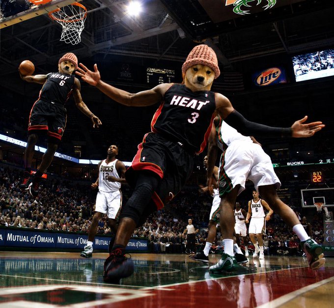 The Miami Heat's mascot Burnie (dressed as a bear with a beanie) reaches out for the ball during an NBA game against the Milwaukee Bucks, with jersey numbers 6 and 3 visible, alongside a "Miller Lite" ad and "Mutual of Omaha" signage on the court. The image relates to the "Wif2 looks crazy, We're gonna make it lads" post by showing the Heat players in action, symbolizing the bullish excitement around the Miami Heat's performance as fans anticipate a winning outcome.