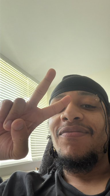 The image shows a person with dreadlocks wearing a black hat, standing up and making a peace sign gesture with their right hand while pointing out towards the camera. The caption of the photo suggests that this person may be participating in an online giveaway for $100 USDC or perhaps won it at a recent event. The post appears to have been drawn from someone who follows a user named "@KibahJoseph" on social media, and they are interested in potentially winning more money through the contest.