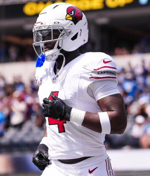 An Arizona Cardinals football player in a white uniform and helmet stands on the field during a game.