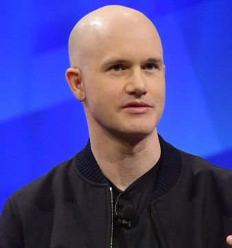 Brian Armstrong, CEO of Coinbase, is shown in a headshot with a shaved head, wearing a dark zip-up jacket, appearing to speak at an event. The image accompanies a post where he discusses continued crypto adoption and stablecoin growth despite the delay of the CLARITY Act.