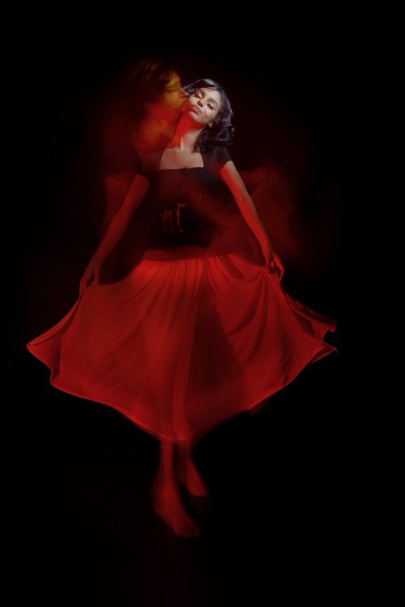 A woman in a flowing red dress appears mid-motion against a dark background, with motion blur creating a dreamy, ethereal effect as she dances or twirls. The image's artistic, dramatic lighting and sense of movement beautifully complement the post's celebration of photography as a creative art form.