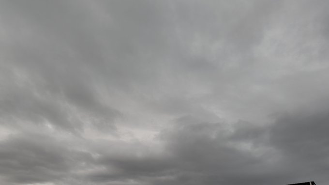 An overcast sky filled with thick gray clouds, with a hint of lighter sky breaking through the middle.
