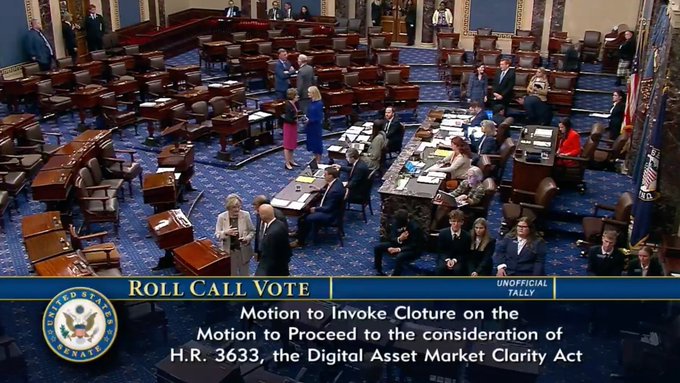 A view of the U.S. Senate floor shows senators gathered during a live roll call vote, as displayed on the chyron: "ROLL CALL VOTE - Motion to Invoke Cloture on the Motion to Proceed to the consideration of H.R. 3633, the Digital Asset Market Clarity Act." The image directly visualizes the post's mention of the CLARITY Act Senate vote being live, with cryptocurrency $XRP positioned as a focal point of the legislation being considered.