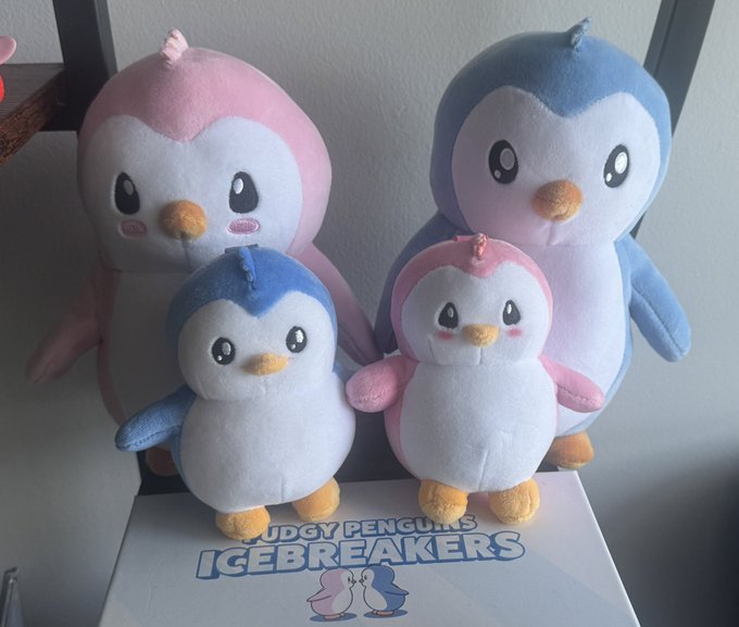 A complete set of four Pudgy Penguins plushies—two blue and two pink—displayed together with the "PUDGY PENGUINS ICEBREAKERS" branding visible on the box below. The arrangement matches the post announcing a full Plushie Set collection.