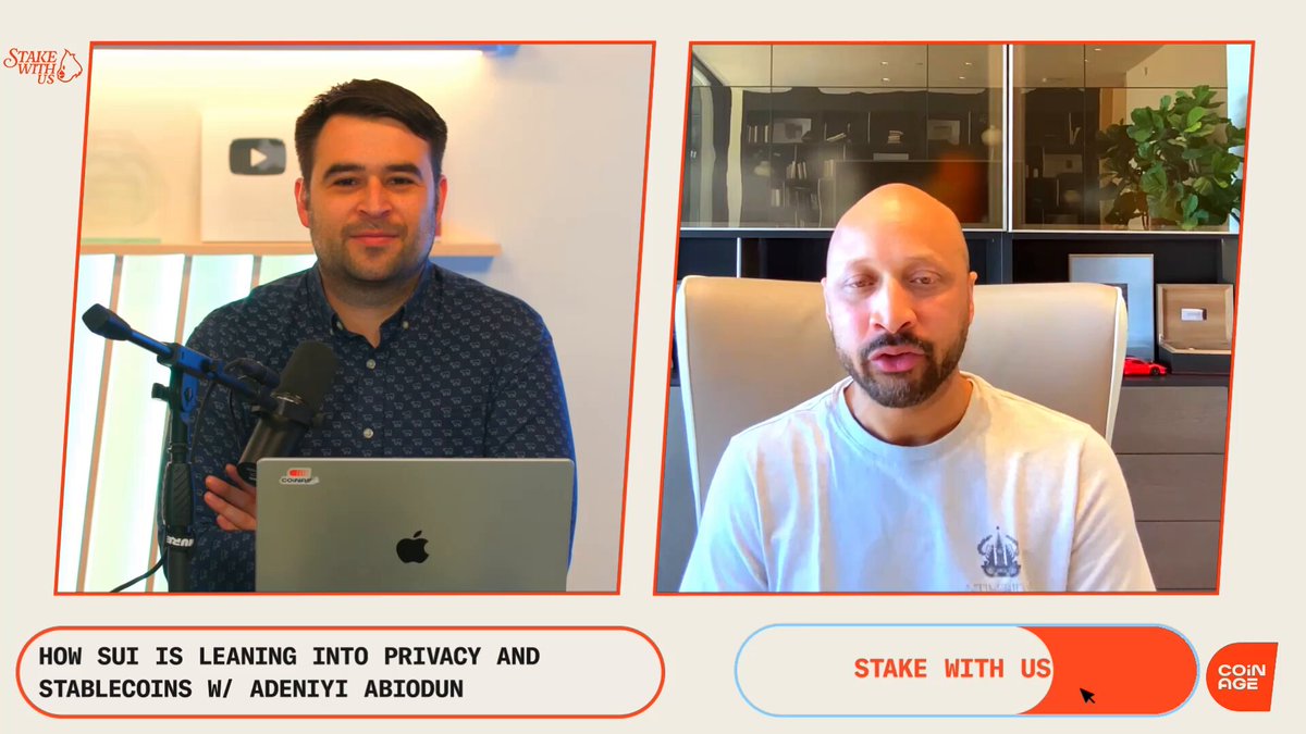 The image shows two men sitting behind a microphone, likely participating in an interview or discussion about privacy concerns related to cryptocurrency. One man appears to be wearing a suit while the other has a bald head. The background features a white wall with a window that allows natural light into the room.