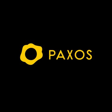 The image shows the Paxos logo, featuring a yellow circular emblem with an organic, wavy shape beside the word "PAXOS" in yellow text on a black background. This logo relates to the announcement that Paxos has added XRP to its regulated crypto brokerage platform.