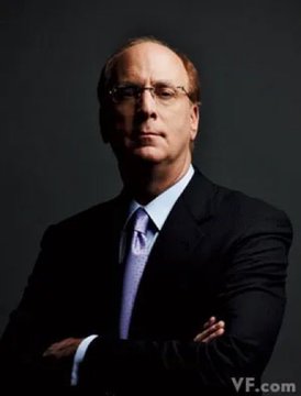 A serious man in a dark suit, glasses, and purple tie stands with his arms crossed against a dark background. The image does not visibly support the accompanying XRP/BlackRock claim, though “VF.com” appears in the lower-right corner.