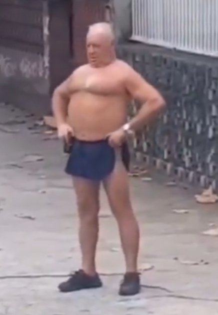 A shirtless older man in dark shorts and shoes stands in what appears to be a parking lot, hands resting on his hips with a wide-eyed, stunned expression on his face. The image humorously captures the "deer in headlights" look, perfectly illustrating the post's joke about someone looking bewildered while watching the Clarity Act unfold.