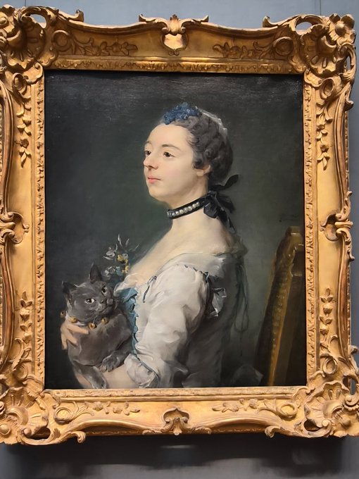 An ornate gold-framed 18th-century portrait painting of a woman in a blue dress holding a gray cat.