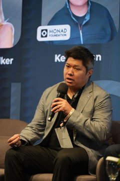 Monad co-founder Keone (visible on the backdrop) speaks into a microphone at the LONGITUDE Singapore conference, with the Monad Foundation logo displayed behind him as he discusses the company's shift toward quantum security and institutional privacy.