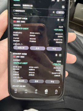 The image shows a person holding a cell phone with a screen displaying various information related to cryptocurrency trading. The person's hand is visible above the phone, while the device is held at an angle against the background. The content on the screen includes details about short positions and their status, as well as the current price of Bitcoin.