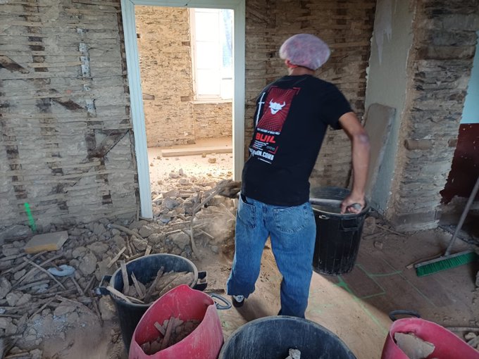 A teen wearing a hairnet and a "Bull Bitcoin" t-shirt hauls rubble in buckets while clearing debris from a gutted room under renovation, illustrating the post's tongue-in-cheek suggestion of using physical "proof of work" labor to discipline him.
