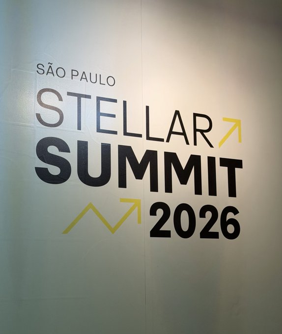 A wall graphic for the 'SÃO PAULO STELLAR SUMMIT 2026' featuring bold black lettering with yellow upward arrows.