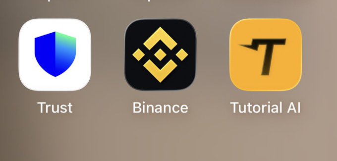 The image features a screenshot of three different logos for Bitcoin, Trust, and Tutorial AI. The first logo displays a shield with a blue background and a yellow diamond shape, representing the Bitcoin logo. The second logo shows a shield with a white background and a yellow diamond shape, symbolizing the Trust logo. The third logo is an illustration of a person holding a book titled "Tutorial AI" in black text against a yellow background. These logos are displayed on a gray background, creating a visually appealing contrast that highlights each brand's unique identity.