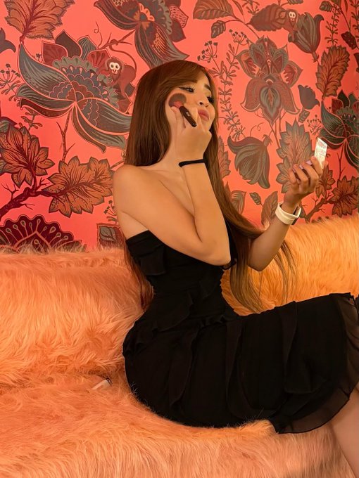 A woman applies makeup with a brush in a bathroom featuring vibrant orange floral wallpaper and an orange faux fur bench, paired with a post reflecting on how Web3 reputation requires multiple metrics rather than a single measurement.