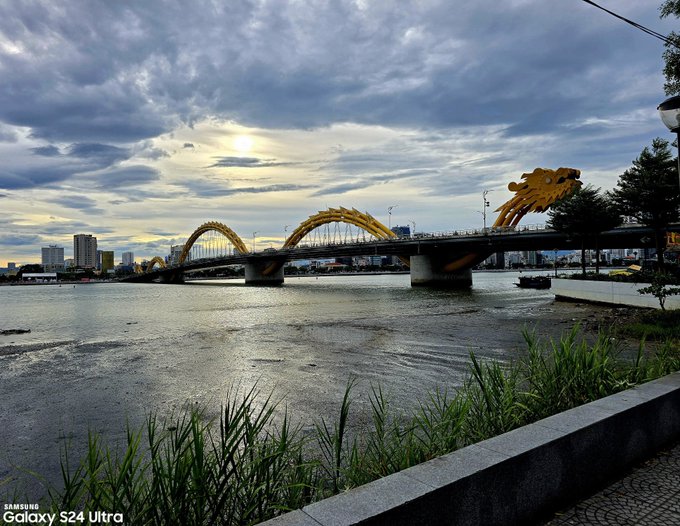 The golden Dragon Bridge spans the Han River in Da Nang under a dramatic sunset sky, captured with a Samsung Galaxy S24 Ultra (as noted in the watermark), perfectly matching the post's reflection on finding peace in quiet sunset moments by this iconic landmark.