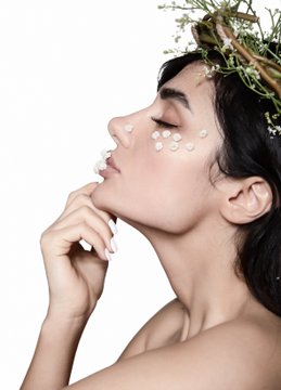A serene woman adorned with delicate white flowers gazes upward, embodying a natural, artistic beauty that complements the handmade aesthetic of the NFT collection being promoted. The ethereal, floral imagery evokes a sense of organic craftsmanship, aligning with the creator's message of personally crafting their art as an alternative to costly therapy.