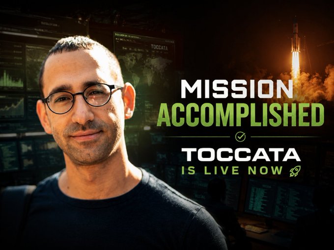 A smiling man with glasses stands in front of a mission control-style backdrop with monitors, beside bold text reading "MISSION ACCOMPLISHED — TOCCATA IS LIVE NOW" with a rocket launching in the background. The image visually celebrates the successful launch of Toccata, aligning with the post's congratulations message and the #Kasha hashtag.
