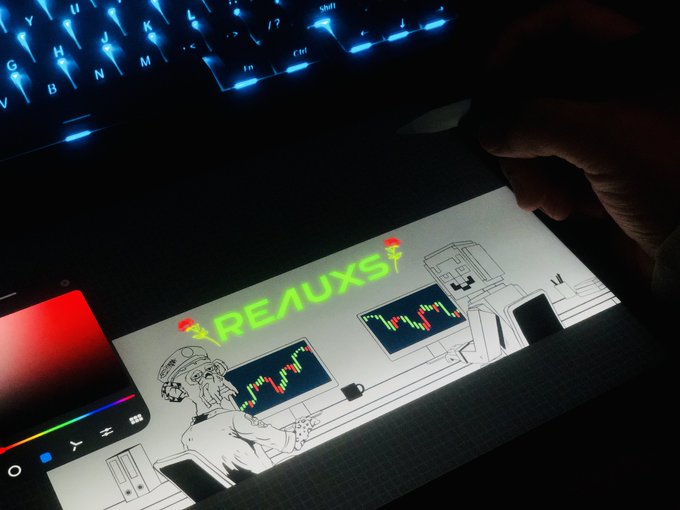 A person's hand using a stylus on a digital drawing tablet displaying an illustration titled 'REALUXS' with characters and trading charts, illuminated by a blue backlit keyboard.