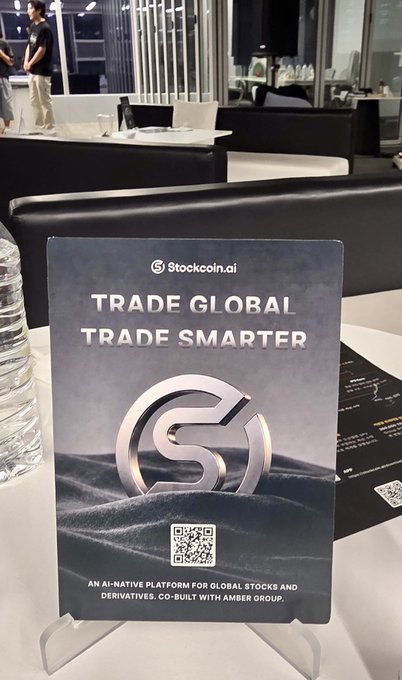A standing promotional sign for "Stockcoin.ai" reading "TRADE GLOBAL TRADE SMARTER - An AI-native platform for global stocks and derivatives. Co-built with Amber Group," featuring a QR code.