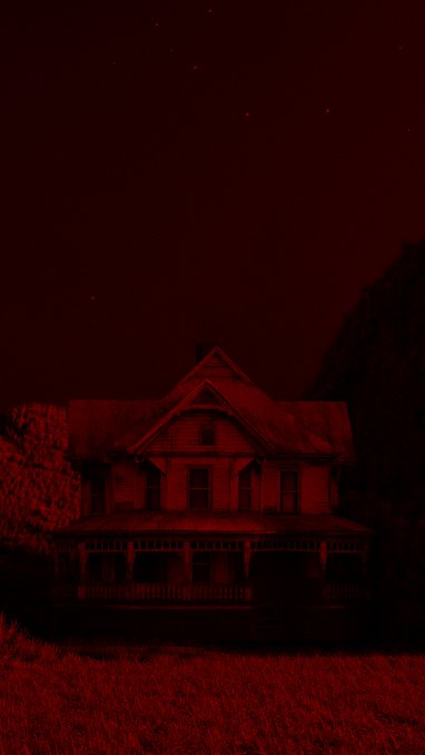 Eerie red-tinted photograph of a Victorian-style house at night with a starry sky, creating a haunting, ominous atmosphere.