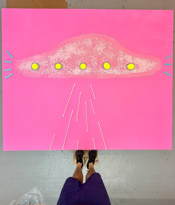 A person's legs and feet visible at the bottom of the frame, standing before a large pink canvas featuring a painted UFO design with yellow lights emitting rays downward.